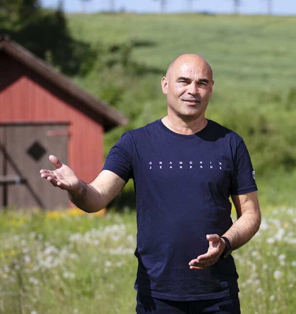 Rune Hunshamar ute på en eng ved et rødt uthus forteller om livsstilsendring og stressmestring